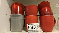 Six ceramic mugs stacked in two rows: three red mugs with glossy and matte finishes on top, two red matte and one gray matte mug on bottom.