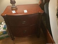 Front view of the mahogany brown wood nightstand showing two drawers and ornamental pulls