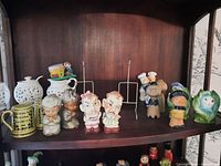 Shelf display of various ceramic items including creamer, sugar bowl, salt and pepper shakers, and figurines