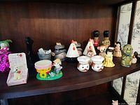 Shelf display of multiple novelty salt and pepper shakers and figurines in various colors and shapes.