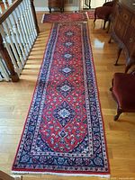 Full-length view of the red and navy floral runner rug on hardwood floor