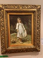 Full view of framed print showing young girl in white dress with a detailed ornate gold frame.