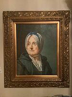 Framed print of an older woman wearing a bonnet with blue ribbons and a dark shawl, in an ornate gold-toned carved frame.