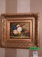 Close-up view of ornate gold-colored frame with intricate scroll and floral ornamentation around the print.