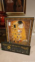 Photo of framed print of Gustav Klimt's 'The Kiss', showing intricate gold and ornamental detail