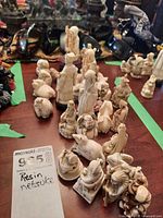 Top-down view of several cast resin netsuke figurines arranged on a wooden surface, showing variety of shapes and sizes.