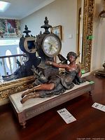 Full view of the resin and stone sculpture with clock, showing the female figure reclining by the clock.