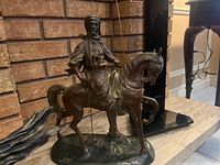 Full view of sculpture positioned on mantel against brick backdrop