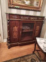 Front view showing marble-style top, upper drawer, central glass-door cabinet and brass mounts.