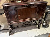 Full front view of sideboard showing carved door panel and decorative stretcher base
