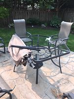 Overall view of square glass-top table with folded umbrella cover on top