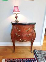 Full front view of the wood base side table with stone top and table lamp on it.