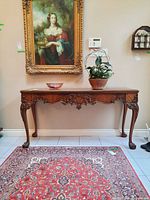 Full front view of carved wooden console table with decorative apron and cabriole legs
