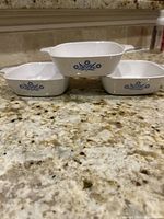 Three white CorningWare rectangular dishes with Blue Cornflower pattern on kitchen counter, showing size and design.