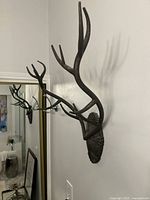 Side view of wall-mounted dark brown metal antler showing multiple branches and rustic textured shield base