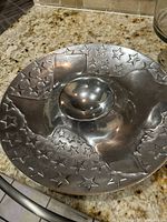 Close-up of pewter serving bowl showing embossed stars and Texas shape design.
