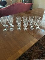 Photo of 12 Lenox Lacepoint crystal glasses arranged on a dining table, showing the set includes both wine and iced tea glasses.