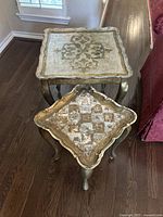 Overhead view showing two vintage wooden decorative side tables in gold finish, one square with floral design, the other diamond-shaped with checkerboard pattern.