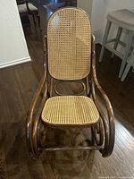 Front view of a vintage wooden rocking chair showing rope cane seat and backrest and curved wood frame.