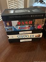 Stack of 7 VHS tapes showing titles M*A*S*H, Andro, Indian in the Cupboard, Ice Castles, The Borrowers