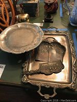 Full view showing ornate rectangular metal serving tray, footed cake stand and crumb catcher with server on top