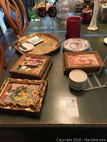 Overview of the table displaying six framed wall prints, decorative wooden platter, porcelain plates, and glassware.