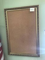 Full view of rectangular cork board with ornate giltwood frame, showing overall size and condition.