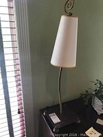 Full view of gooseneck table lamp with white tapered fabric shade, metallic curved neck, and copper/brass base.