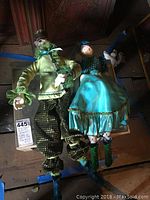 Pair of tall fancy cat figurines dressed in colorful and decorative clothing.