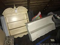 Two painted wooden wall shelves; larger with ornate carved top and finial, smaller with drawers.