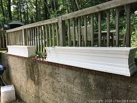 Two long white resin planters placed outdoors on a raised ledge, highlighting their size and condition.