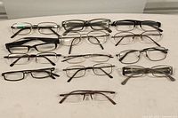 Photo showing all 13 eyeglass frames laid out in rows on a white surface.