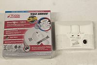 Photo of the two alarms together: one boxed new Kidde Pro Series smoke and CO alarm and one unboxed CO alarm.