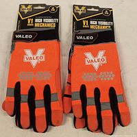 Two pairs of orange and black Valeo work gloves still in factory packaging with V1 Series High Visibility Mechanics branding and size large label.