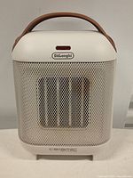 Front view of Delonghi ceramic fan heater with mesh grille and handle