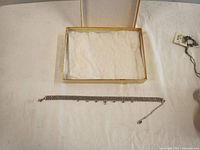 Photo of entire necklace laid flat on white fabric with box top nearby