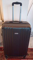 Full front view of dark brown textured hard shell suitcase with telescopic handle extended.