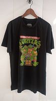 Full front view of black XL T-shirt with Teenage Mutant Ninja Turtles colorful graphic.
