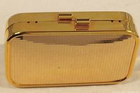 Closed view of the gold tone metal purse showing the textured exterior surface and hinged clasp.