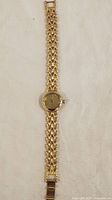 Full photo of the gold-tone ladies wristwatch laid flat showing linked bracelet band