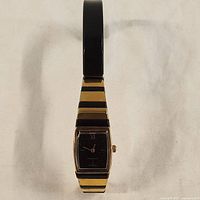 Full view of the watch with the band extended showing alternating gold and black stripes.