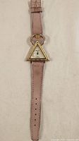Full view of the wristwatch showing the triangular face and pink leather strap.