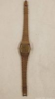 Full view of gold tone Timex wristwatch with linked metal band lying flat.
