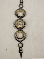 Full view of the wristwatch with silver-tone and gold-tone circular linked band laid flat.