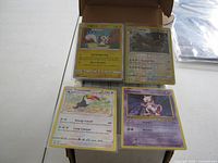 Four Pokémon cards laid out including one Japanese language card and English language cards (Toucannon, Mewtwo).