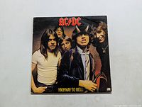 Front cover of AC/DC Highway to Hell album showing the band with Angus Young wearing devil horns and holding a pitchfork.