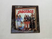 Front cover of Black Sabbath Sabotage vinyl LP showing band members and illuminated frame with album title.