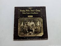 Front cover of the album showing worn black cover with sepia photo of the band and dog, with gold lettering.