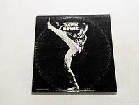 Front cover of David Bowie The Man Who Sold The World vinyl LP showing Bowie performing a high kick in black and white.