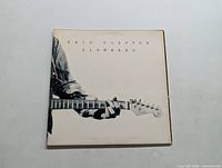 Front cover of Eric Clapton's Slowhand vinyl album with close-up of guitar neck and hand.